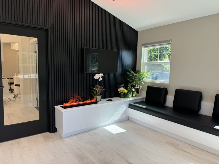 Modern dental office waiting area at Mona Lisa Smile Dental in Walnut Creek, featuring black and white interior, TV, and electric fireplace