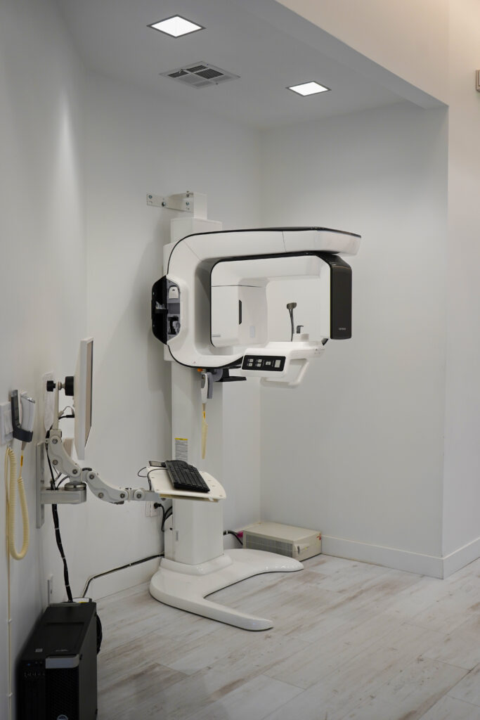 A state of the art white 3D dental imaging machine standing in a modern clinical room at Mona Lisa Smile Dental.